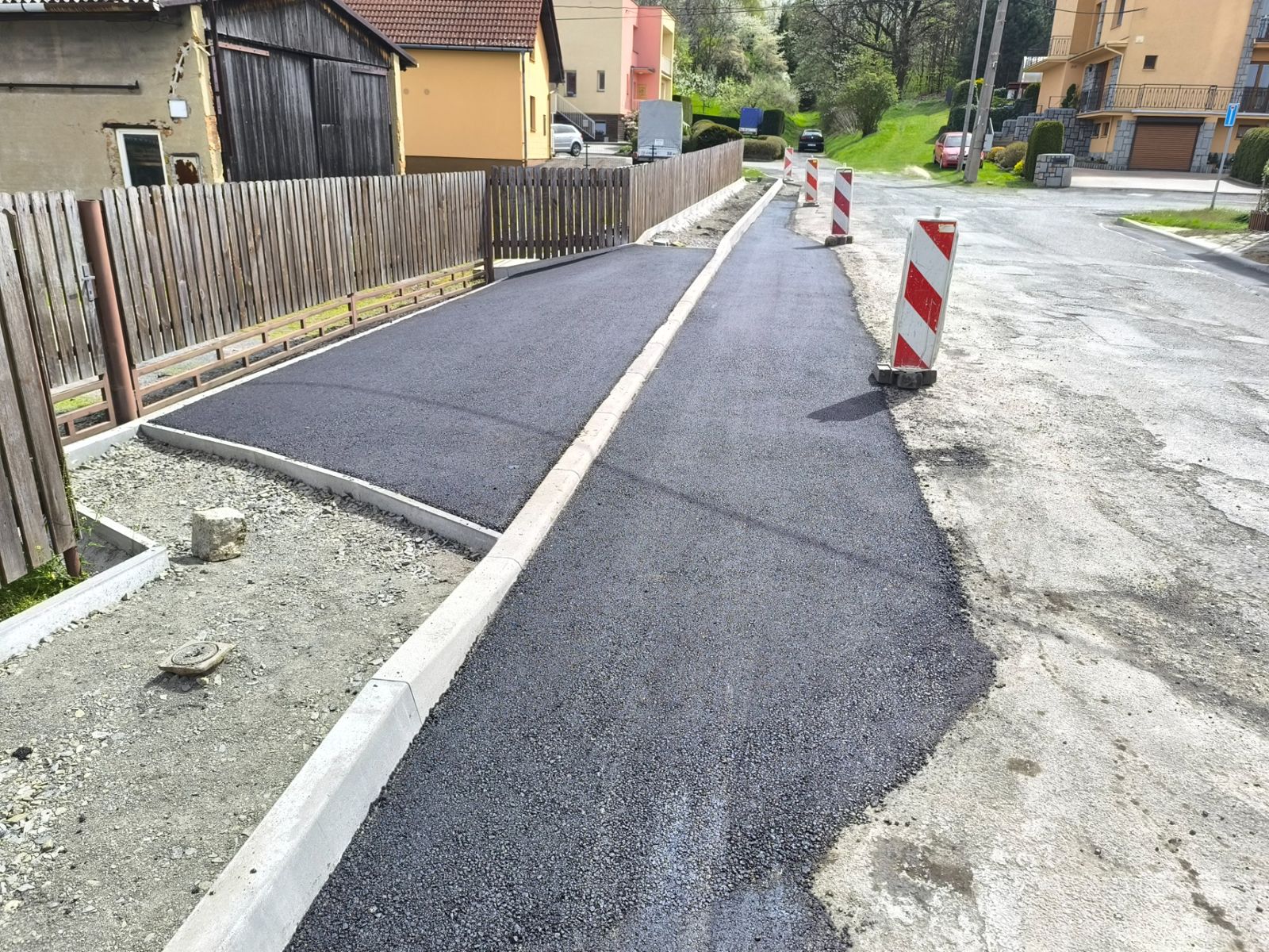 Nově položený asfaltový chodník podél plotu